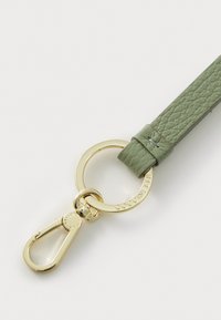 Green leather strap with a textured finish, featuring gold-tone hardware and a circular ring with the brand name engraved.