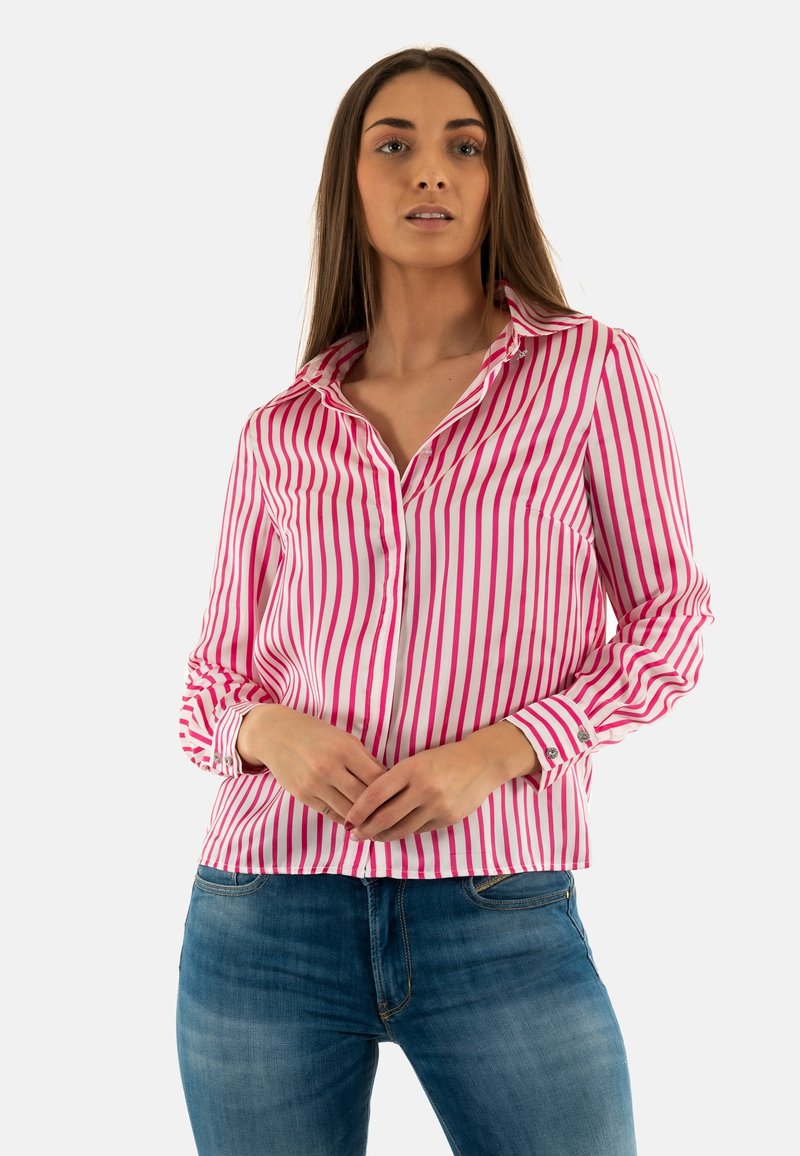 Camisa de botones a rayas rosas y blancas con cuello y mangas largas, con acentos en los puños. Llevada con jeans azules. Textura de tejido suave.