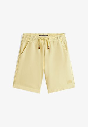 Żółte szorty z elastycznym paskiem w talii i sznurkiem do regulacji. Dwie boczne kieszenie oraz fakturowany detal logo na dolnym brzegu. Gładka tkanina.