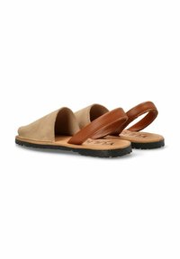 Sandalias de ante beige sin hebillas con una tira de cuero marrón, suela plana de goma negra y un forro interior suave. Diseño minimalista sin patrones adicionales.