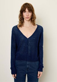 Granatowy kardigan, dekolt w serek, długie rękawy, wykonany z teksturowanej, lekkiej dzianiny. Posiada pięć guzików z przodu, casualowy krój.