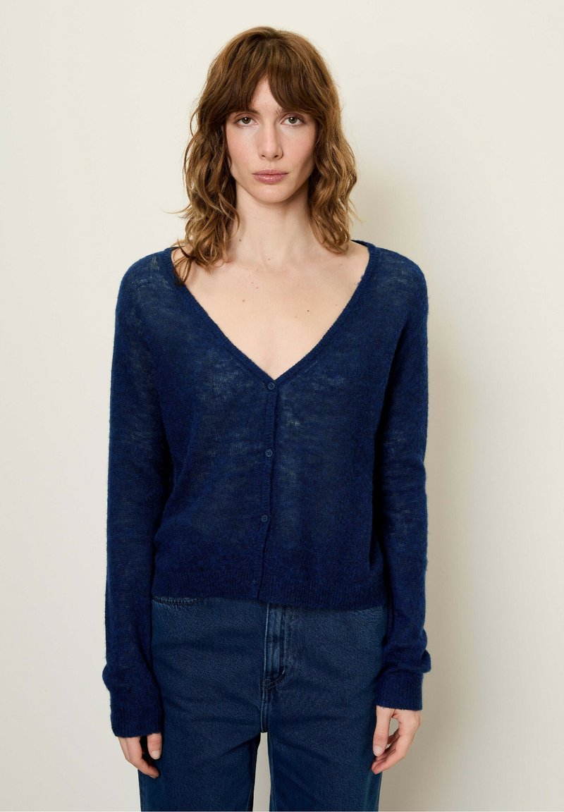 Granatowy kardigan, dekolt w serek, długie rękawy, wykonany z teksturowanej, lekkiej dzianiny. Posiada pięć guzików z przodu, casualowy krój.