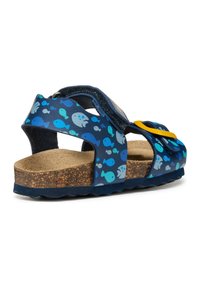 Sandali blu navy con un motivo di pesci in tonalità di blu e grigio, cinturini regolabili, soletta in sughero e suola in gomma testurizzata.