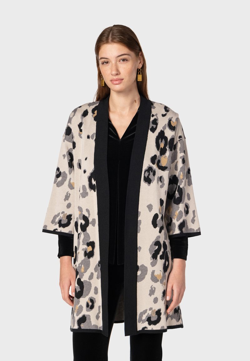 Leren jasje met luipaardprint in beige, zwart en grijs, met een open voorkant, kimono-mouwen en contrasterende zwarte afwerking. Zachte brei-textuur.