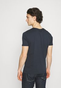 Marineblå bomulls T-skjorte med korte ermer og rund hals, med en glatt tekstur og en tettsittende design, kombinert med jeans.