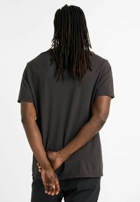 Dark gray short-sleeve t-shirt made from smooth fabric; features a relaxed fit and a rounded hem with no visible patterns or graphics.