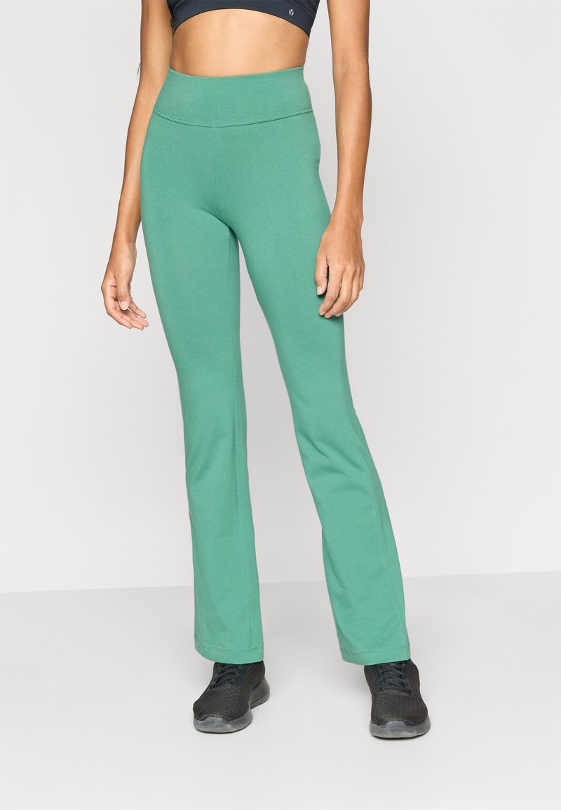 Πράσινο παντελόνι καμπάνα από απαλό, ελαφρύ ύφασμα με ψηλή μέση. Συνδυάζεται με μαύρα αθλητικά παπούτσια. Απλός και λειτουργικός σχεδιασμός.
