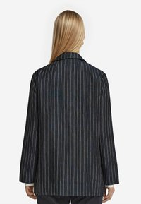 Mörkblå, rutigt kavaj med avslappnad passform, som har en ren halsringning och långa ärmar. Materialet har en texturerad yta.