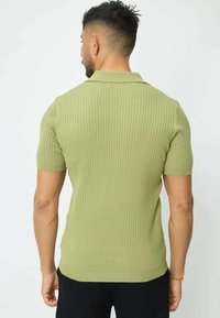 Polo à manches courtes côtelé en vert clair. Doté d'un col classique et d'un léger stretch dans un tissu tricoté texturé.