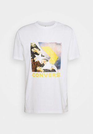 Weißes T-Shirt mit kurzen Ärmeln und einem bunten Converse-Logo mit Blumen, einem Stern und einem gelben Pfeil auf der Vorderseite.
