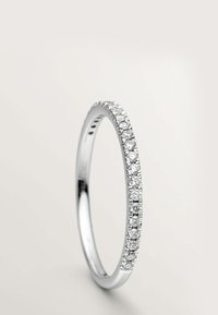 Anillo de plata delgada con una fila de pequeños diamantes blancos redondos engastados a lo largo de la mitad superior de la banda sobre un fondo liso.