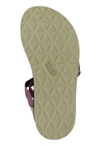 Semelle de sandale Teva avec un motif triangulaire, couleur beige clair, bonne adhérence. Sangle violette visible sur le côté, montrant un design durable.