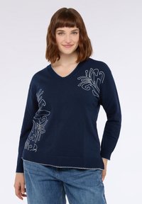 Jersey de punto navy con escote en V y mangas largas. Presenta bordado floral blanco en el lado izquierdo y un dobladillo texturizado.