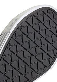 Black rubber shoe sole with a triangular pattern. Grey fabric upper edge with white accents. Textured surface for grip and durability.