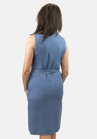 Vestido azul sin mangas hecho de tela texturizada, con un cinturón en la cintura y bolsillos laterales, con un dobladillo hasta la rodilla.