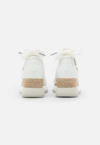 Paire de baskets à plateforme en cuir blanc avec semelles intermédiaires tissées beiges et lacets ruban crème noués en nœuds, vues de dos.