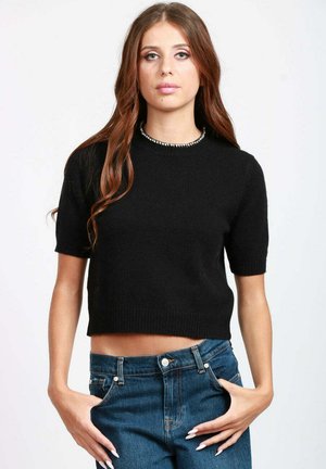 Maglione nero corto con maniche corte, scollatura tonda e dettagli di perline sul colletto. Indossato con jeans blu a vita alta. Morbido al tatto.