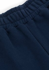 Granatowe spodnie dresowe z miękką, polarową teksturą, wyposażone w elastyczny pas i zwężane nogawki zapewniające komfort i swobodę ruchów.