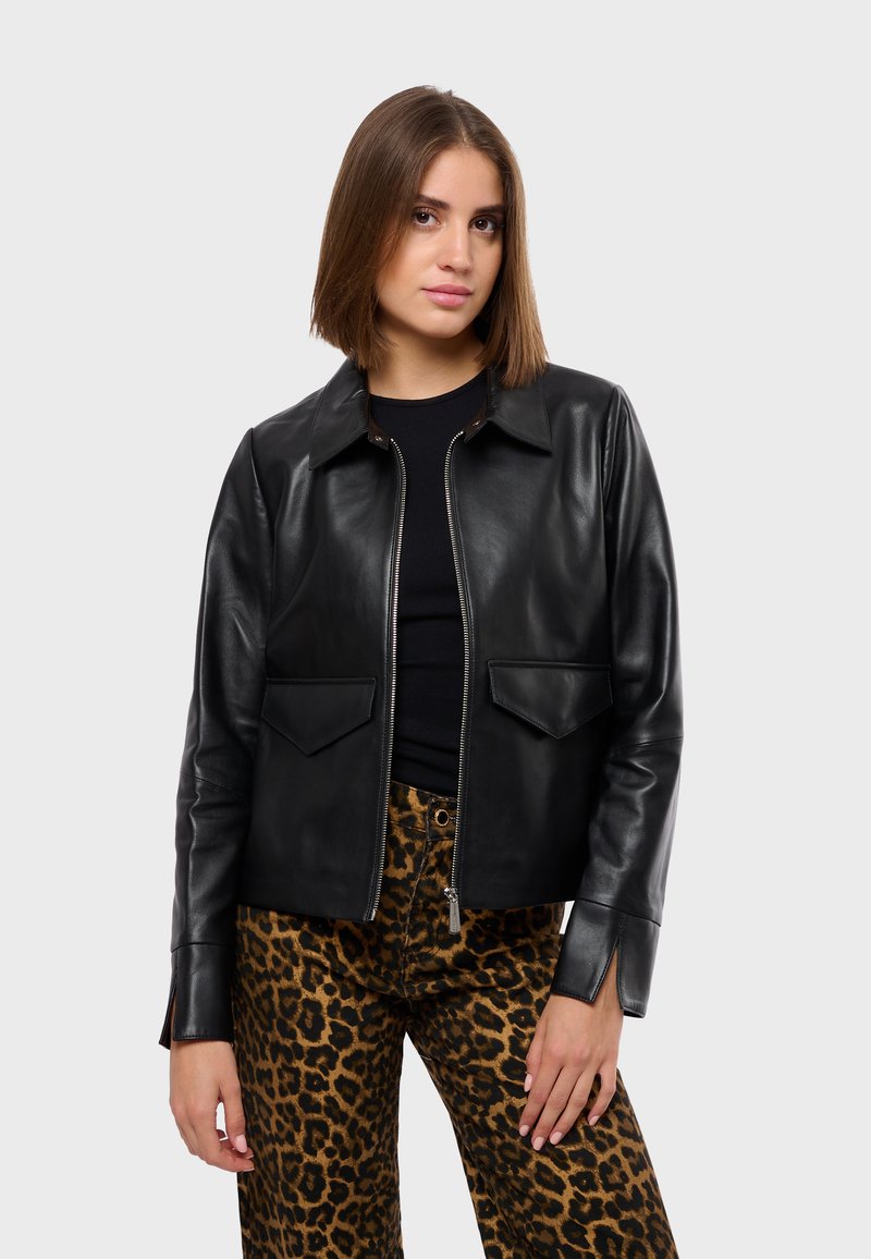 Black leather jacket with a pointed collar, front zip, two patch pockets, and long sleeves, paired with leopard print pants.
