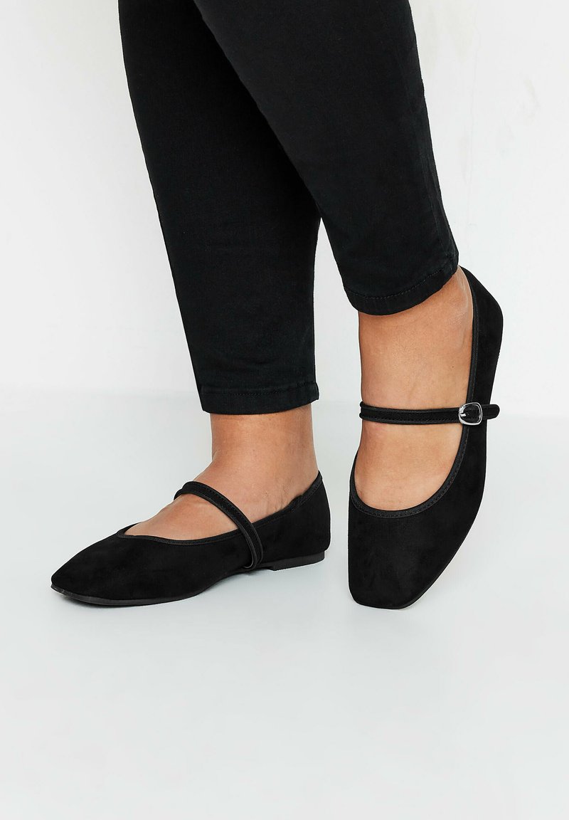 Bailarinas negras de ante con diseño de punta afilada y una delgada tira en el empeine, que presenta una pequeña hebilla decorativa a un lado.