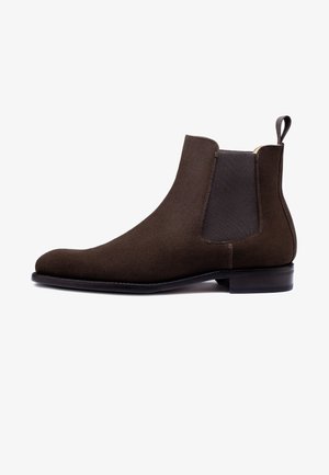 Bottines Chelsea en suède marron avec des panneaux élastiques sur les côtés, un bout arrondi lisse et un petit talon empilé. Tirant à l'arrière pour un enfilage facile.
