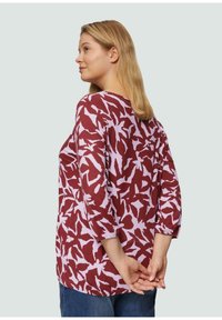 Bordeaux blouse met roze abstracte patronen, losse pasvorm, driekwart mouwen en ronde halslijn. Zachte stof met een ontspannen vorm.