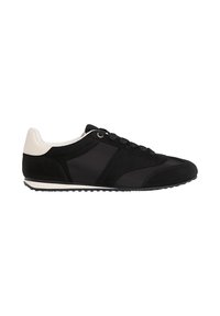Chaussures de sport noires avec un dessus en suède texturé, des accents synthétiques lisses et un talon crème contrastant. Elles présentent des lacets traditionnels et une semelle en caoutchouc.