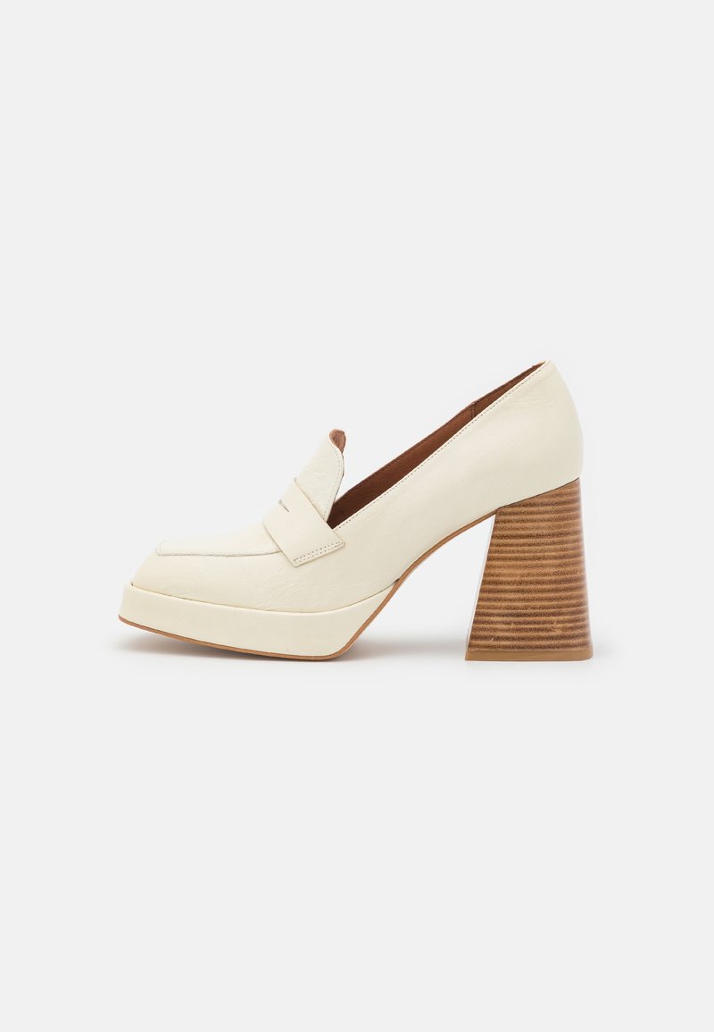 Mocassin plateforme en cuir crème avec large talon en bois empilé et design à enfiler sur fond blanc.