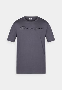 Camiseta de algodón gris con mangas cortas, que presenta un logo bordado de "Champion" en el pecho y un pequeño logo en la manga.