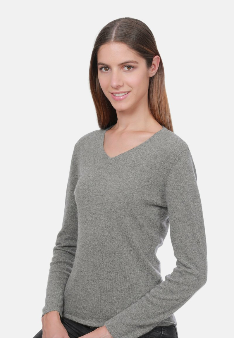 Pull en V gris en tricot doux, avec des manches longues et une coupe ajustée. Texture lisse sans motifs ni embellissements visibles.