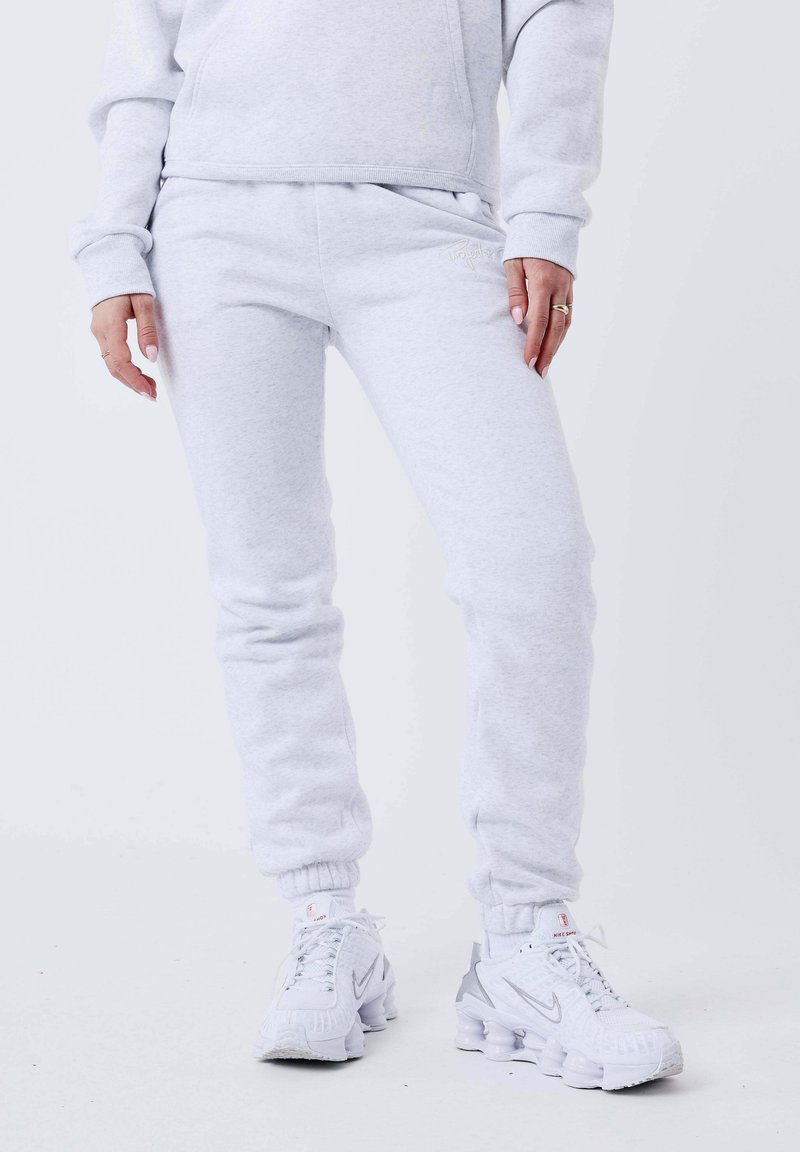 Lichtgrijze sweatpants met een comfortabele pasvorm, elastische boorden en zakken, gecombineerd met witte en zilveren sneakers. Gemaakt van een zachte katoenmix.