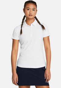 Polo bianco con colletto e tre bottoni, realizzato in tessuto liscio. Indossato con una gonna blu scuro; il modello presenta capelli intrecciati.