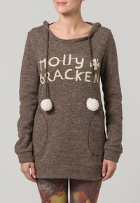 Felpa con cappuccio marrone con testo "Molly Bracken" in crema, due pompon decorativi e tasche frontali; materiale a maglia testurizzato.