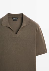 Polo shirt marrone a maniche corte realizzato in tessuto leggero, con scollatura a V e colletto ripiegato, dalla texture liscia e dal design minimalista.
