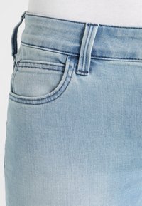 Ljusblå denimjeans med en klassisk femfickdesign. Funktioner inkluderar en mid-rise midja och subtila slitage detaljer.