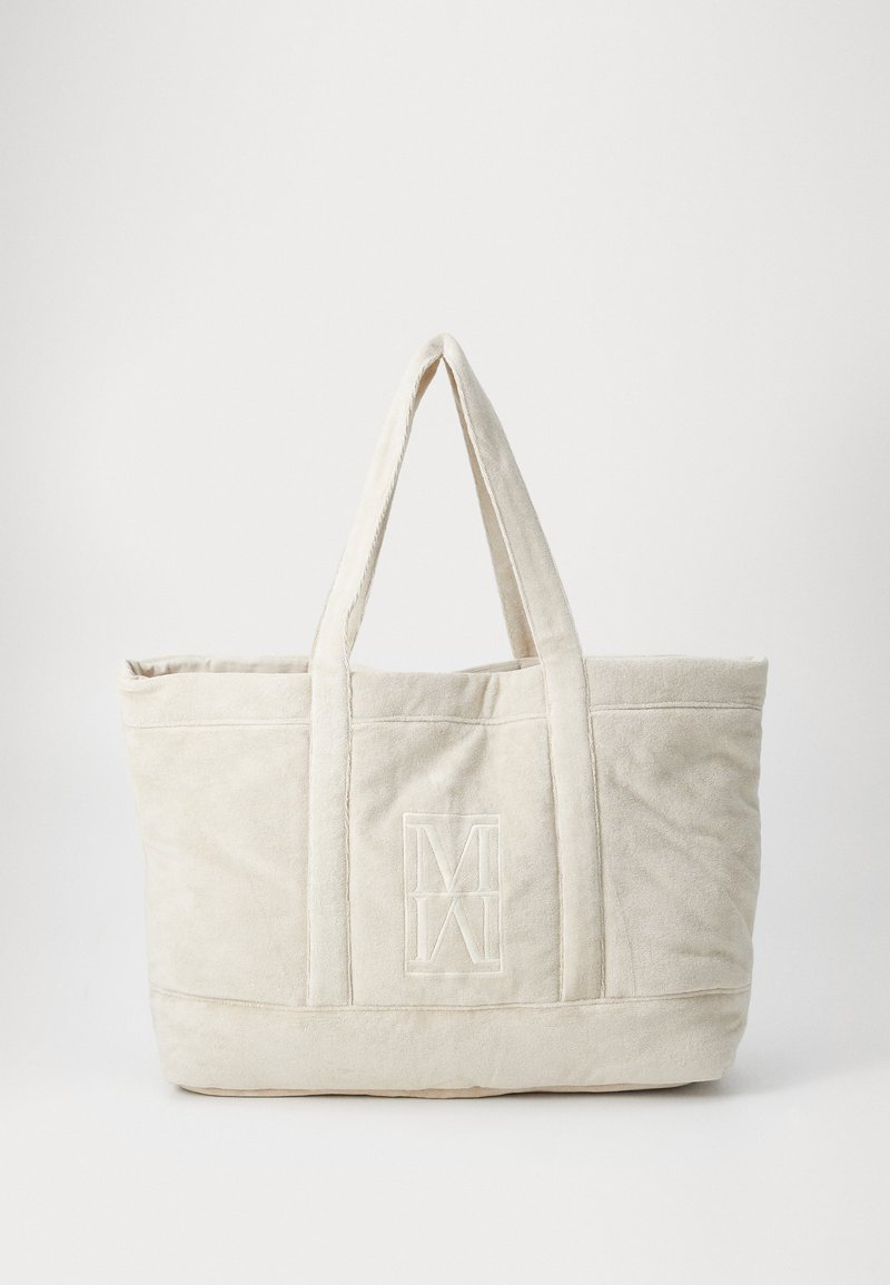 Sac fourre-tout en toile beige avec de courtes poignées, doté d'un logo brodé sur le devant, texture douce et design structuré.