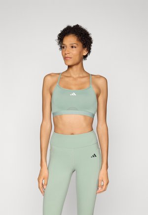 Light green sports bra with adjustable straps and a cut-out design, paired with matching high-waisted leggings featuring black logo accents.