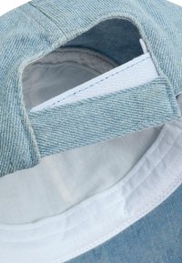 Denim sapka világoskék textúrával, belül fehér anyaggal bélelve. Az állítható pánton fehér címke és kék varrás található.