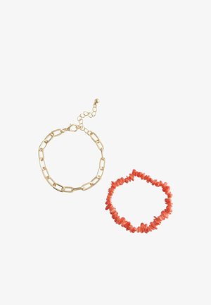 Gold chain bracelet with large links and clasp, and stretchy bracelet made of small irregular red coral beads on white background.