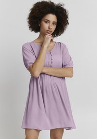Lila Kurzarmkleid mit V-Ausschnitt, Frontknöpfen und gerafftem Taillenbereich. Hergestellt aus leichtem strukturiertem Stoff, knielang mit fließender Silhouette.