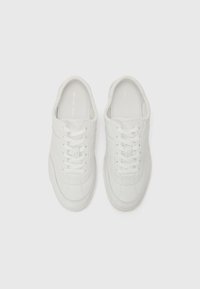 White leather sneakers with a smooth texture, featuring diagonal stitching, standard laces, and a subtle logo on the tongue.