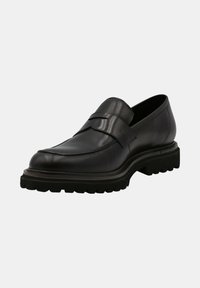 Mocassin en cuir noir avec une finition lisse, présentant une sangle décorative sur le dessus, et une semelle en caoutchouc épaisse et texturée.
