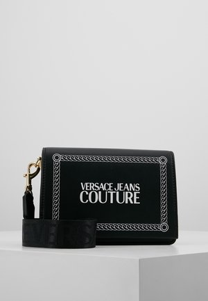 Czarna prostokątna torba Versace Jeans Couture z białym wzorem obramowania z liny oraz odpinanym czarnym paskiem z złotym zapięciem.