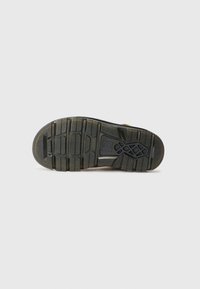 Black rubber sole with deep treads and pronounced grooves. Features textured patterns and reinforced areas for durability.