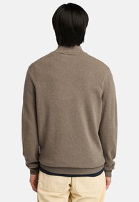 Maglione marrone a maglia con colletto rotondo, polsini e orlo a costine. Il design appare semplice e presenta una consistenza morbida.
