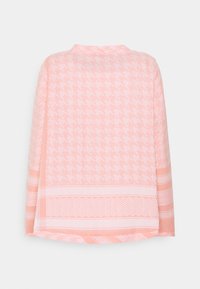 Jasnoróżowa, pleciona koszula w wzór w psią zębatkę, z krótkimi rękawami i kontrastującymi poziomymi paskami na dole. Prosty okrągły dekolt.