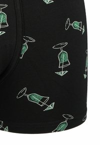 Czarne bokserki z powtarzającym się wzorem zielonych klepsydr i strzałek. Wykonane z miękkiego, elastycznego materiału o gładkiej fakturze.