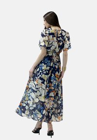 Abito maxi blu con fiori, maniche a sbuffo corte, vita elastica e dettaglio a occhiello sul retro. Realizzato in tessuto leggero e trasparente.