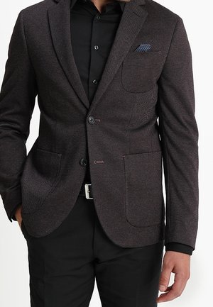 Blazer texturé marron foncé avec un revers cranté, deux poches, fermeture à un bouton et un mouchoir de poche à motif bleu clair.