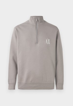 Lysegrå kvart-zip trøje lavet af blødt materiale, med et lille hvidt logo på brystet samt elastiske manchetter og kant.